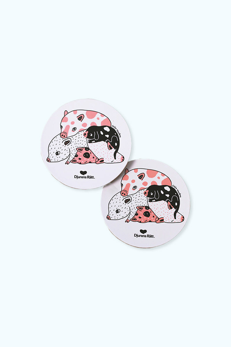 Två glasunderlägg med en illustration av flera grisar som ligger i en hög och Djurens Rätts logga