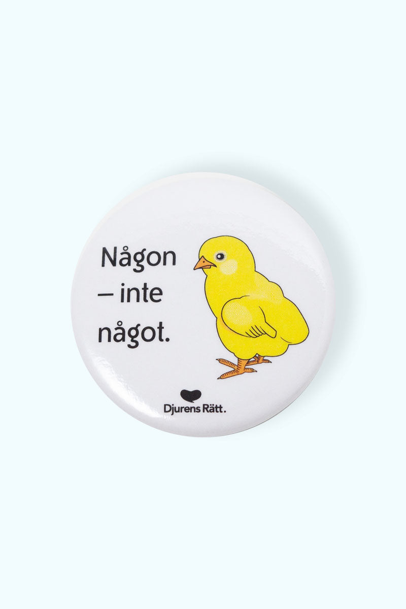 Vit pin med illustration av en kyckling och texten "Någon inte något" och Djurens Rätts logga