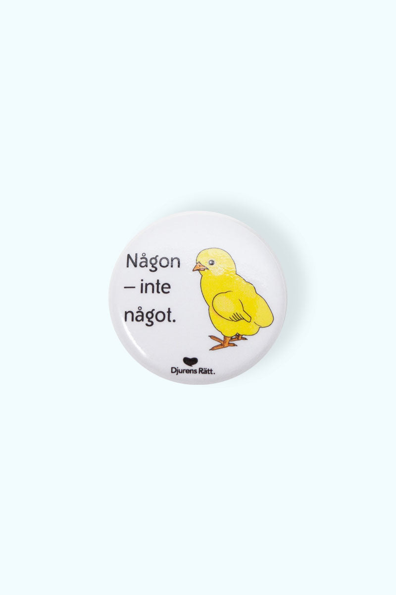 Vit liten pin med illustration av en kyckling och texten "Någon inte något" och Djurens Rätts logga